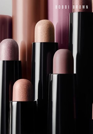 Variety of Bobbi Brown lipsticks in black cases, showcasing multiple nude and pink shades with matte and shimmer finishes.