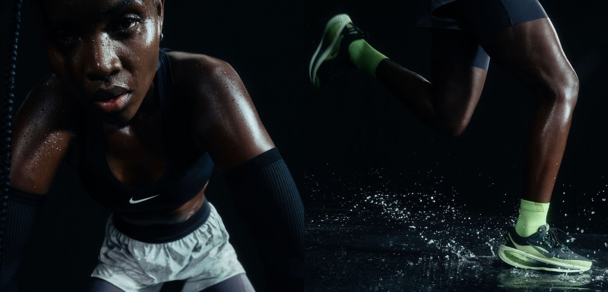 Atleta in canotta nera senza maniche e pantaloni corti chiari, con sudore che luccica sulla pelle. Maniche nere, espressione concentrata, sfondo scuro.