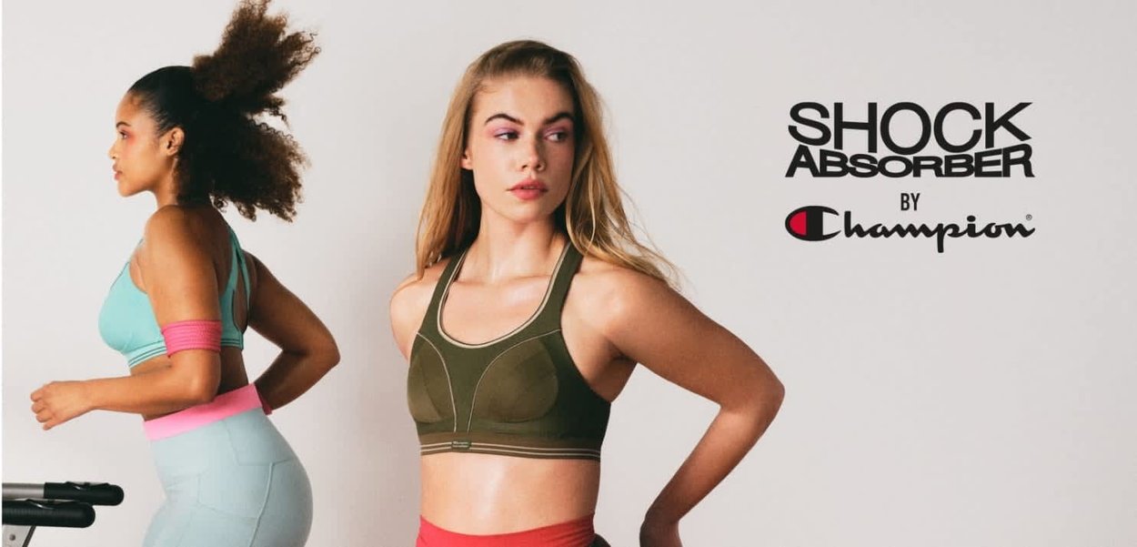 Dos mujeres con ropa deportiva, una corriendo en una cinta de correr y la otra de pie con las manos en las caderas, promoviendo Champion Shock Absorber.