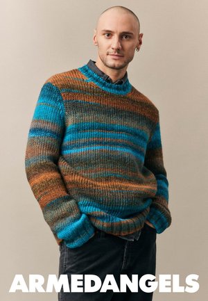 Übergroßer Strickpullover mit blauen, braunen und grünen Streifen. Gerippter Halsausschnitt und Bündchen. Modell trägt dunkle Jeans, keine sichtbaren Muster.