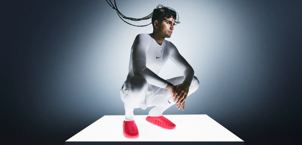 Zapatos rojos tipo slip-on con suelas texturizadas, usados por una persona con un conjunto blanco ceñido, agachada en una plataforma blanca contra un fondo oscuro.