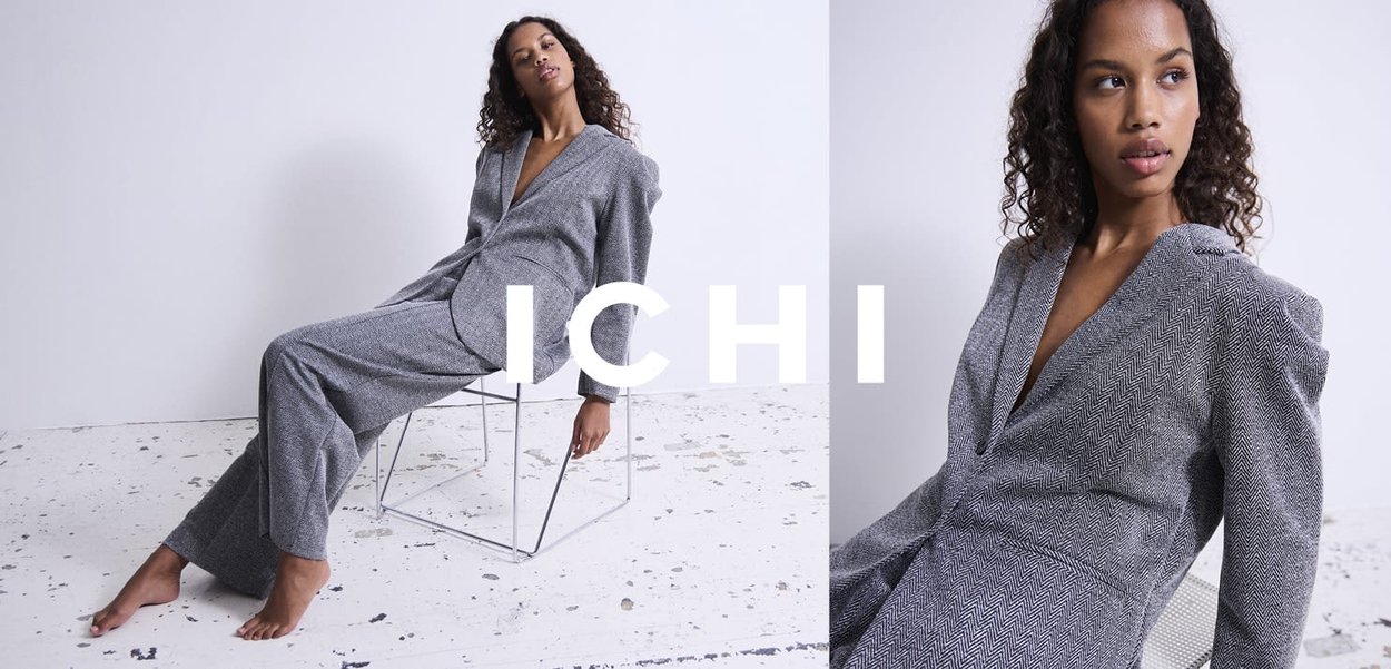 Combinaison gris pied-de-poule avec un décolleté en V profond, un détail d'épaule oversize, et une coupe décontractée, associée à une chaise en métal minimaliste.