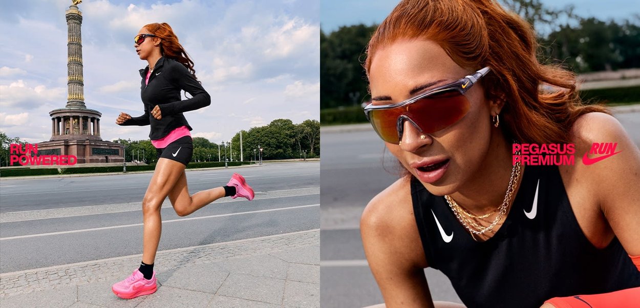 Chaqueta atlética negra y pantalones cortos con acentos rosas, zapatillas de correr rosas, gafas de sol reflectantes y un fondo de un monumento en un parque.