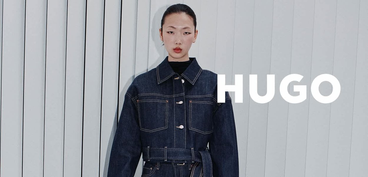 Kurtka dżinsowa z dwoma kieszeniami na piersiach, zapięciem na guziki i paskiem w talii. Charakteryzuje się kontrastowymi przeszyciami i usztywnionym kołnierzem. Kolor ciemnoniebieski.