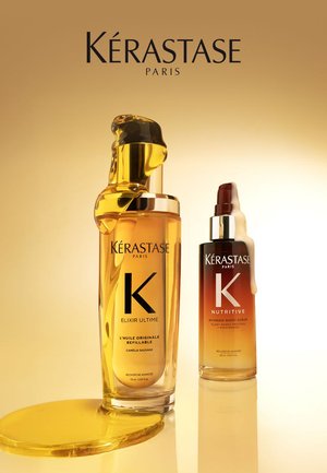 Due prodotti per la cura dei capelli Kérastase: una bottiglia alta e trasparente di olio dorato con un cappuccio nero e oro, e una bottiglia di siero corta e marrone. Entrambi su una superficie riflettente.