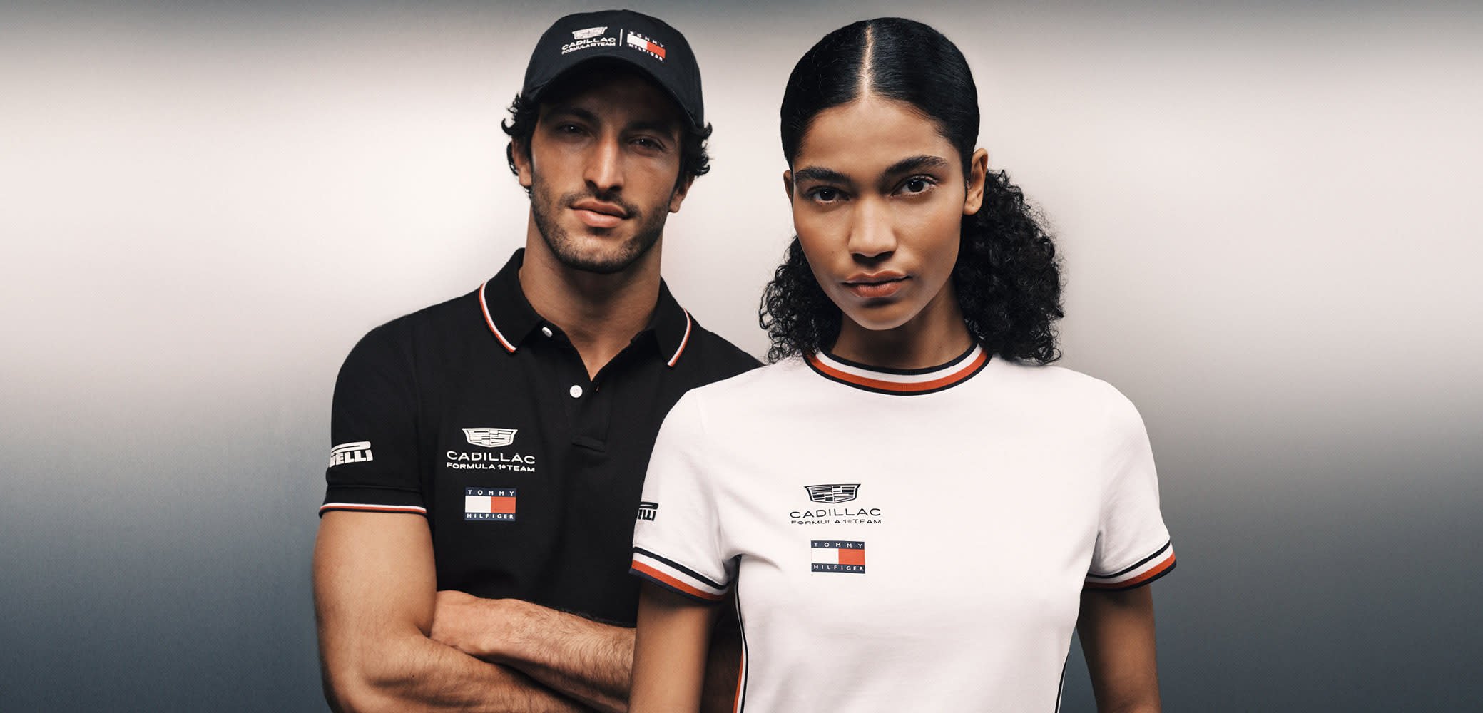 Deux mannequins portant des polos noirs et blancs de l'équipe Cadillac Formula E, posant devant un fond dégradé avec des expressions sérieuses.