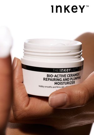 Hvid rund fugtighedscremekrukke med et sort mærkat med teksten "Bio-Active Ceramide Repairing and Plumping Moisturizer." Glat tekstur, delvist åben.