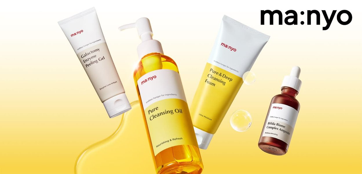 Vier huidverzorgingsproducten weergegeven: een witte tube, een amberkleurige fles, een gele tube en een bruine druppelfles, allemaal gelabeld met "ma:nyo."