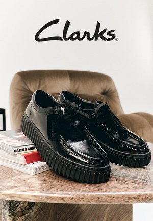 Chaussures en cuir noir avec une finition brillante, languette rembourrée et semelle en caoutchouc épaisse. Présentent un laçage à l'avant et un logo en relief sur le côté.