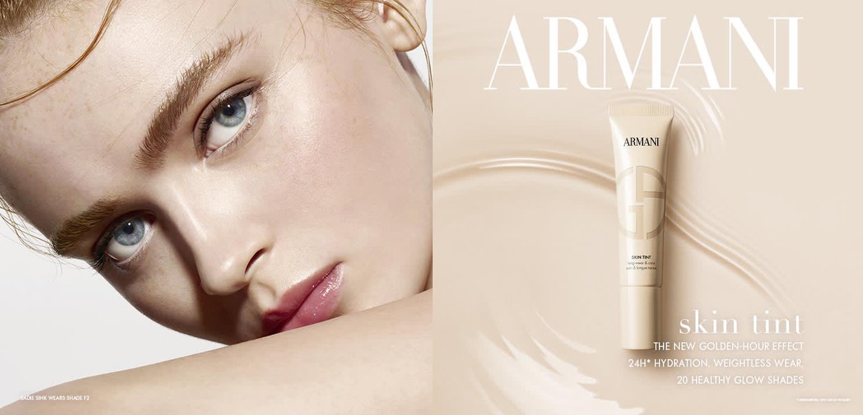 Armani skin tint in a light tube features a sleek design. Prominent text highlights hydration and 20 shade options, set against a soft beige background.