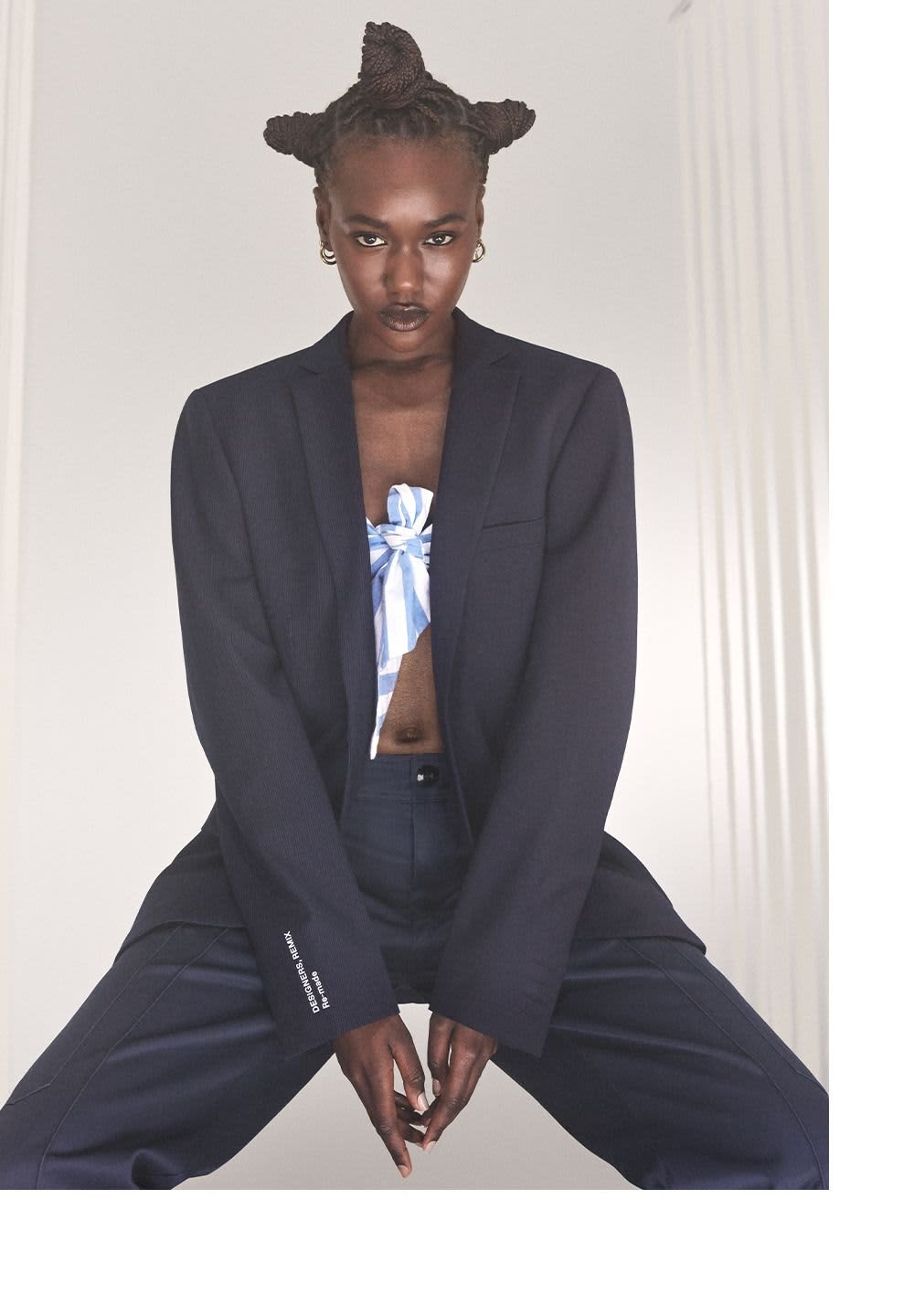 Navy blazer featuring a textured fabric, single-button design, and contrasting white text on the sleeve. Paired with a blue and white patterned top.