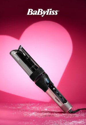 Coiffeur à air chaud rotatif BaByliss sur une surface rose avec des particules scintillantes et une lumière en forme de cœur en arrière-plan.