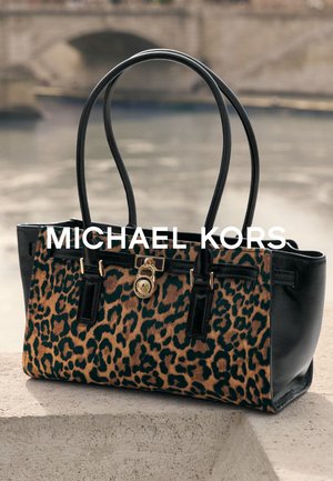 Sac cabas en cuir noir avec un motif léopard, des détails en métal doré, et des doubles poignées pour un port facile.