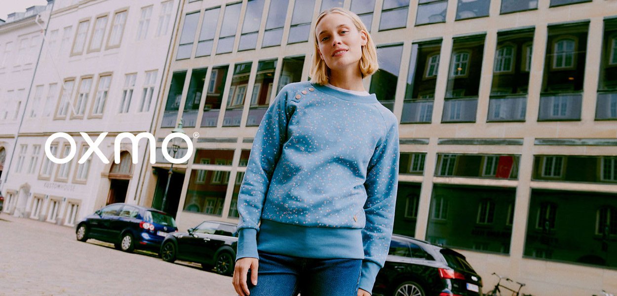 Sweat-shirt bleu clair à pois éparpillés, col rond, avec des détails de boutons sur l'épaule, associé à un jean bleu.