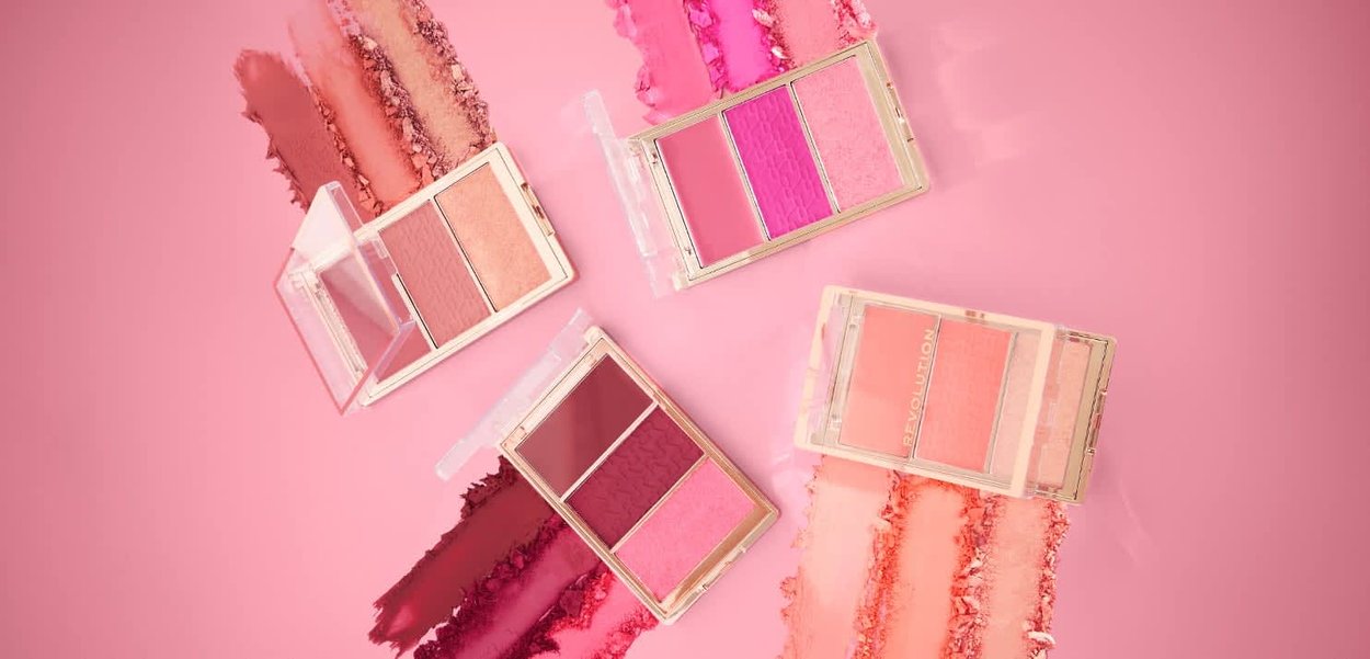 Fire kompakte blush-paletter med to farger, som inneholder en blanding av rosa, fersken og bærtoner på en rosa bakgrunn med teksturerte overflater.