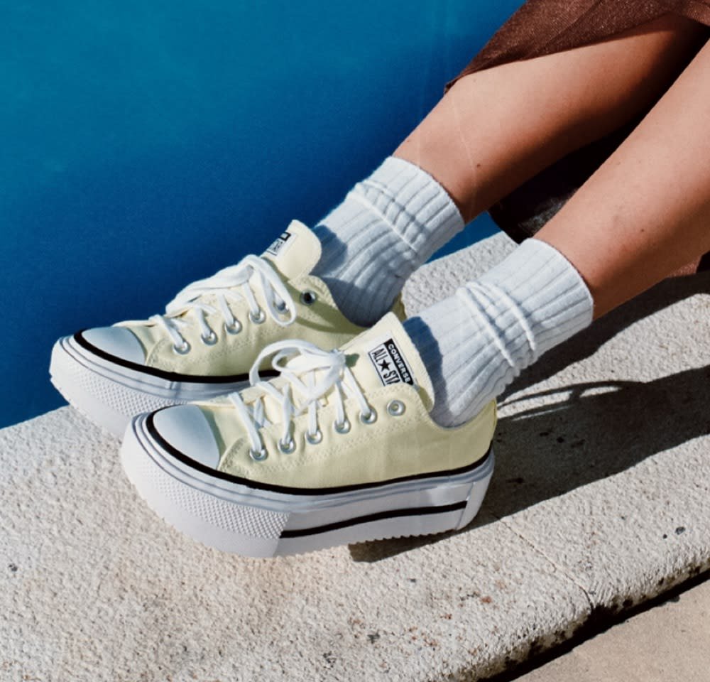 Yellow canvas platform sneakers with white rubber sole and black stripes, paired with light gray ribbed socks.