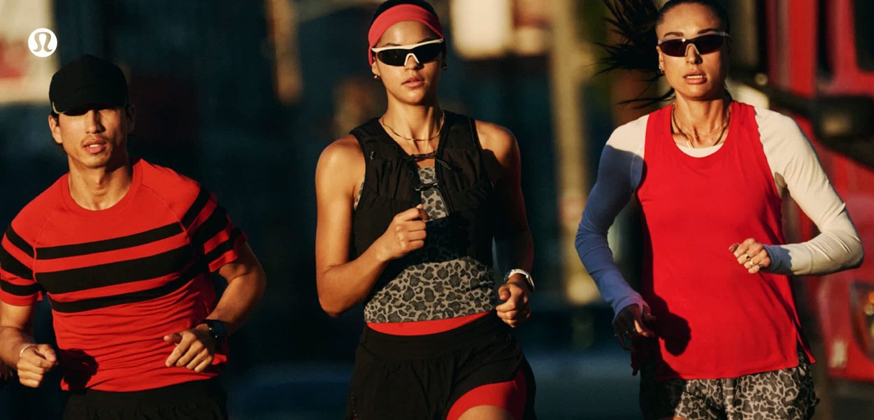 Tres personas con ropa deportiva y gafas de sol corriendo al aire libre durante el atardecer o el amanecer.