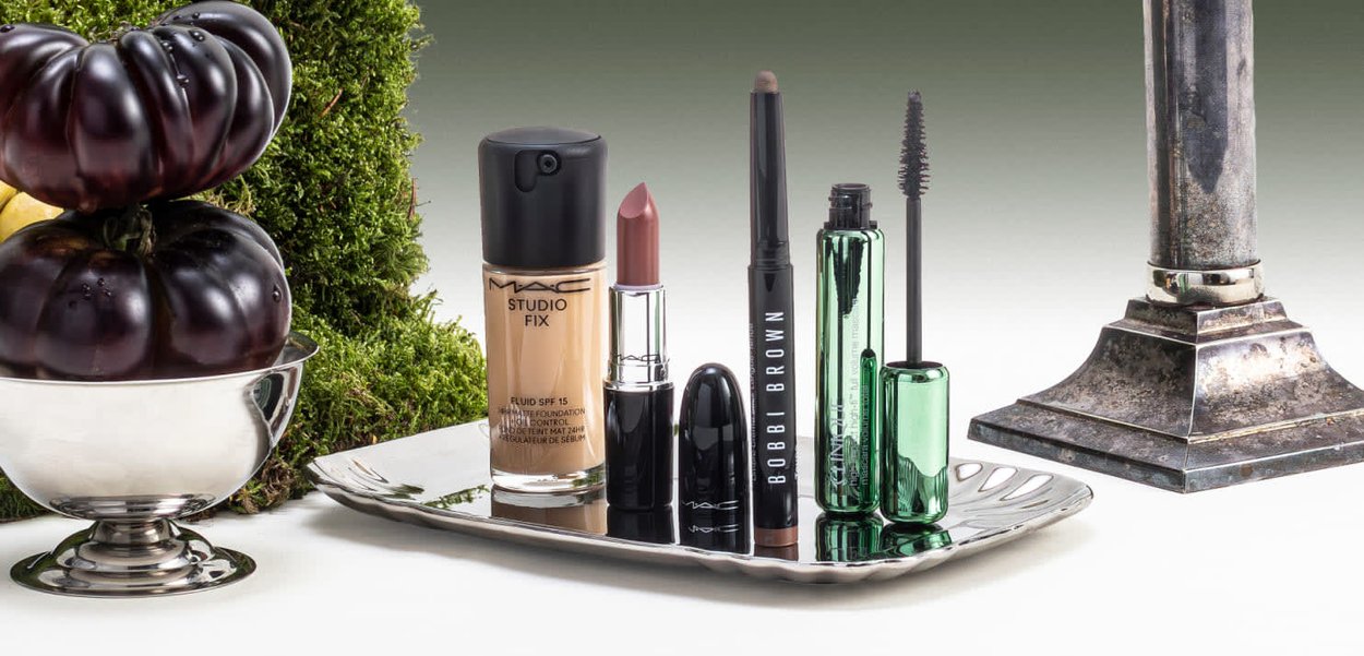 MAC Studio Fix foundation (glasfles), lippenstift (metalen huls), Bobbi Brown eyeliner (zwart), mascara (groene huls) op een zilveren dienblad.