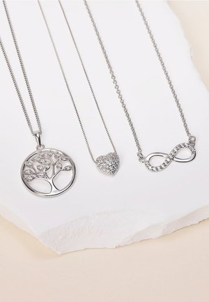 Tre collane d'argento: un ciondolo albero della vita, uno a forma di cuore con scintillii e un simbolo d'infinito, tutti appesi su uno sfondo chiaro.