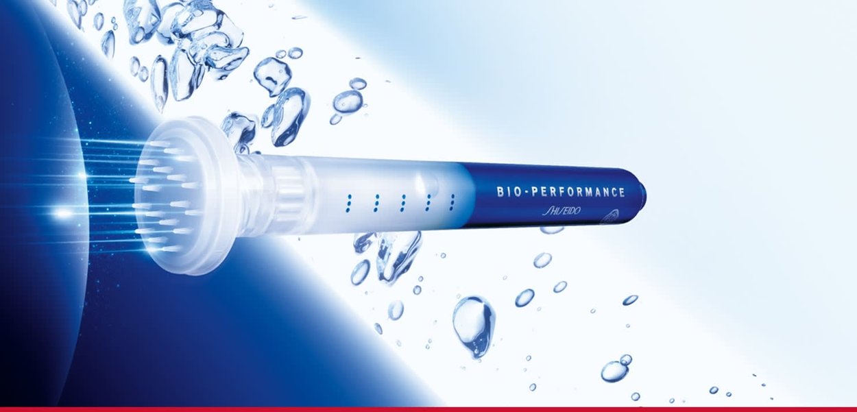 Shiseido Bio-Performance toestel: cilindrisch blauw lichaam met een witte doorzichtige spuitmond, gestructureerde punt en verlichte ontwerpelementen, omgeven door waterdruppels.