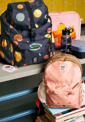 Rygsække lavet af stof; en med mørk baggrund og farverige himmelmønstre, den anden i pink med et katteansigt. Andre genstande inkluderet.