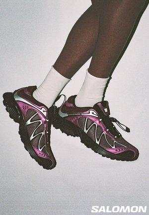 Salomon sportssko med et design i lilla og sort, med en tekstureret mesh-overdel, gummisål og reflekterende detaljer.