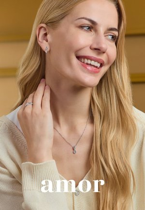 Silberne Ohrringe und eine Halskette mit einem Tropfenanhänger. Das Model trägt einen leichten Pullover, hat lange blonde Haare und natürliche Schminke. Einfaches Design.