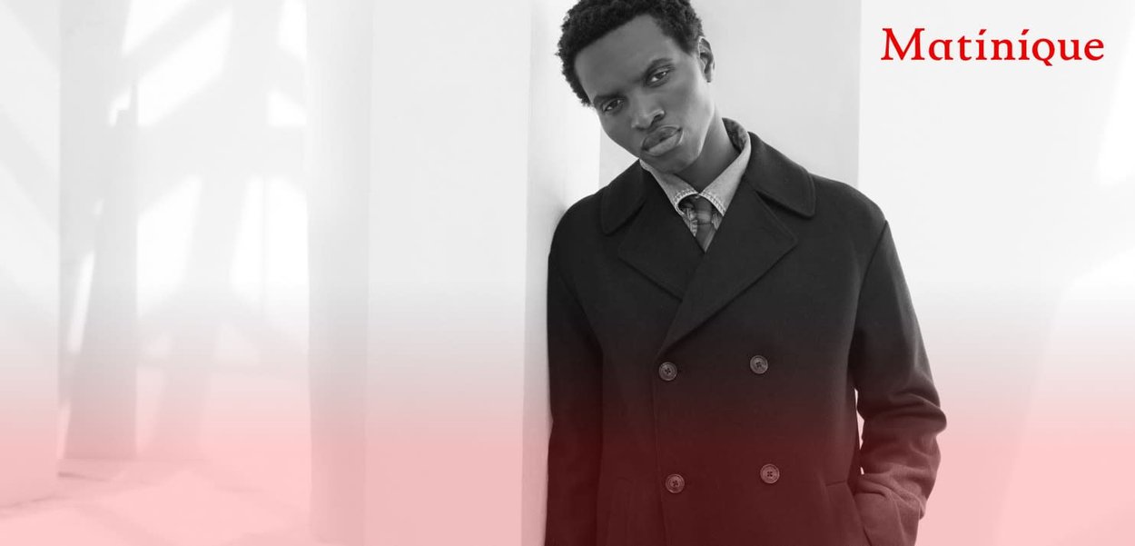 Manteau noir à double boutonnage en laine, avec de gros boutons et un col à revers, assorti à une chemise à motifs et une cravate.