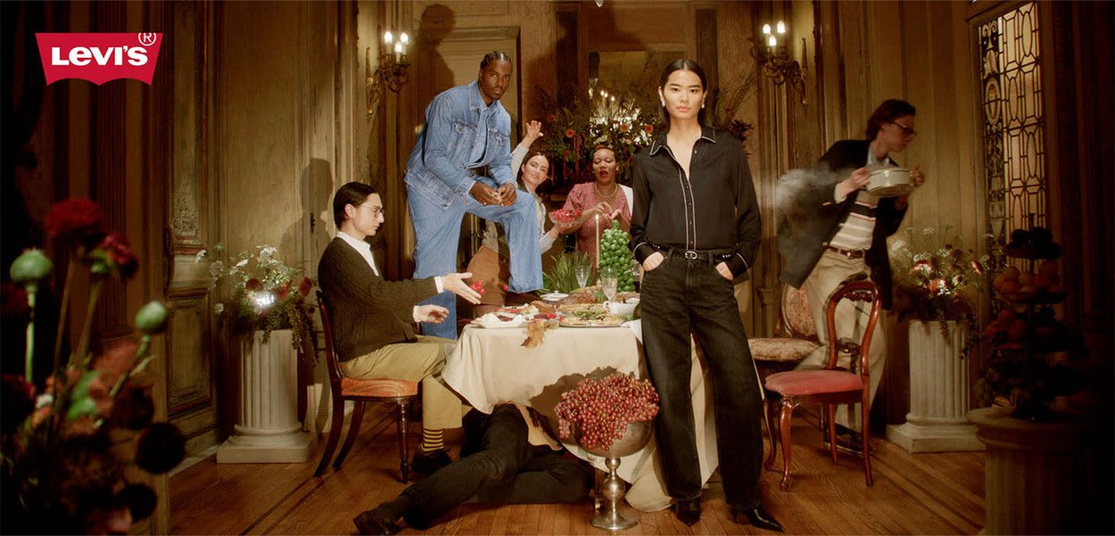 Jean et chemise Levi's noirs, le mannequin se tient en évidence parmi une réunion festive avec une table dressée et des accents floraux décoratifs.