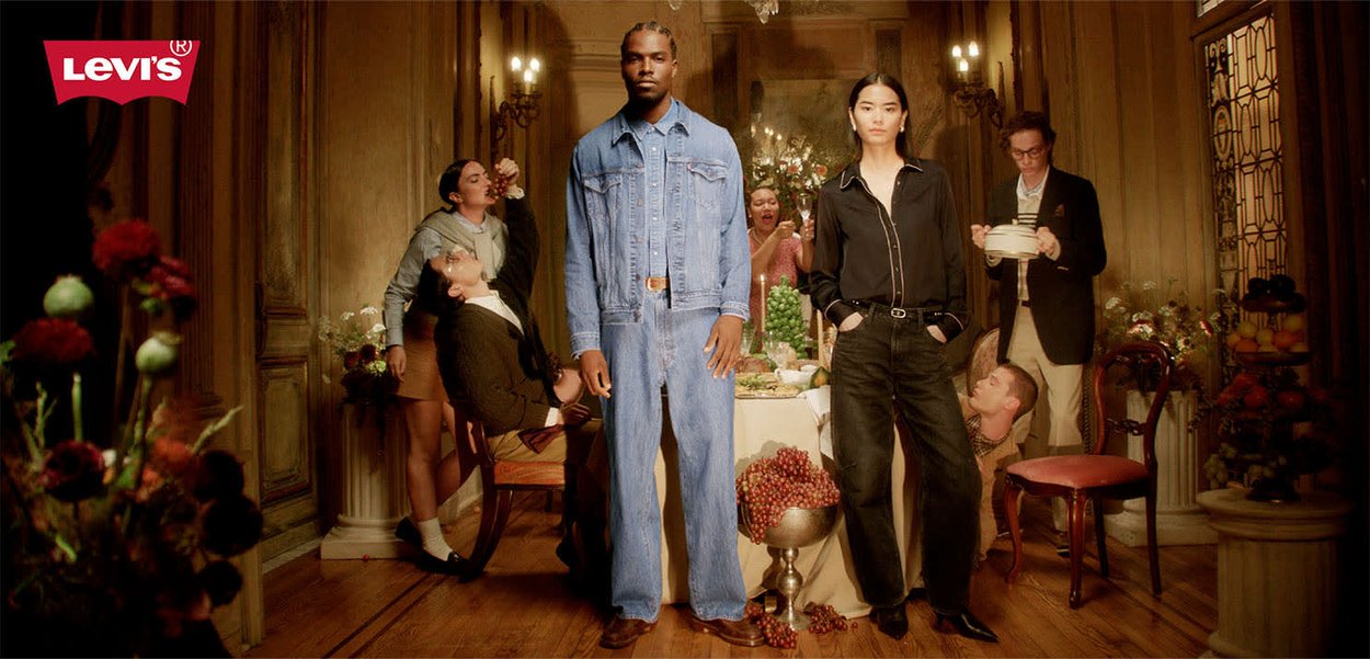 Giacca e jeans in denim Levi's azzurri, accompagnati da una blusa nera e pantaloni. Ambientazione in una stanza ornata con decorazioni floreali e tavolo da pranzo.