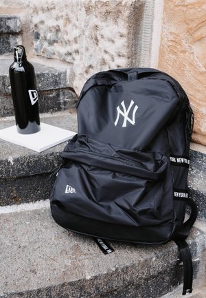 Zaino nero con un prominente logo bianco dei New York Yankees, dotato di un tessuto testurizzato, tasca frontale con zip e spallacci regolabili.