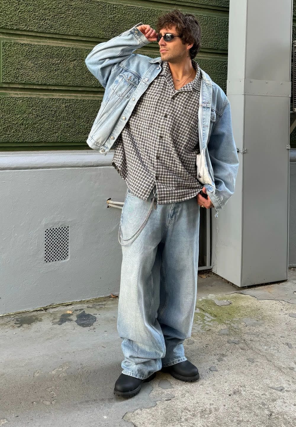 Hele sinine teksajakk, ruuduline lühikeste varrukatega särk, helesinised laiad teksad, mustad paksud kingad ja prillid.