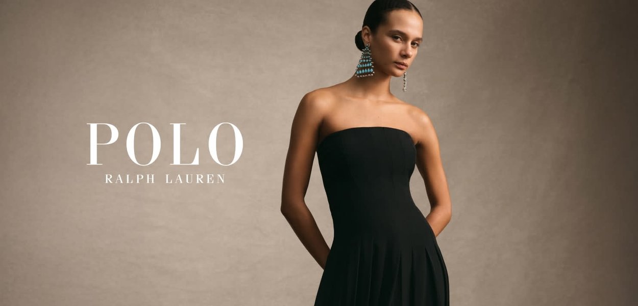 Robe noire sans bretelles avec un corsage ajusté et une jupe évasée, présentant une texture lisse. Grandes boucles d'oreilles pendantes avec des accents bleus.