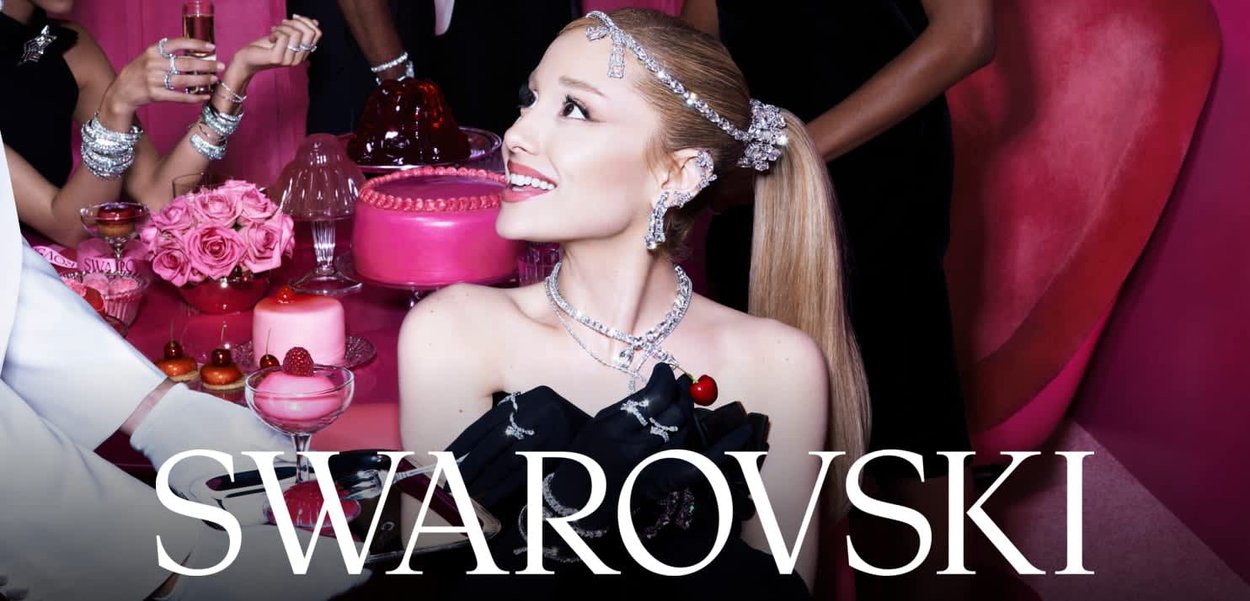 Bijoux Swarovski sur un mannequin, avec des accents en cristal clair, un detailing complexe et une robe noire élégante sur fond rose vif.