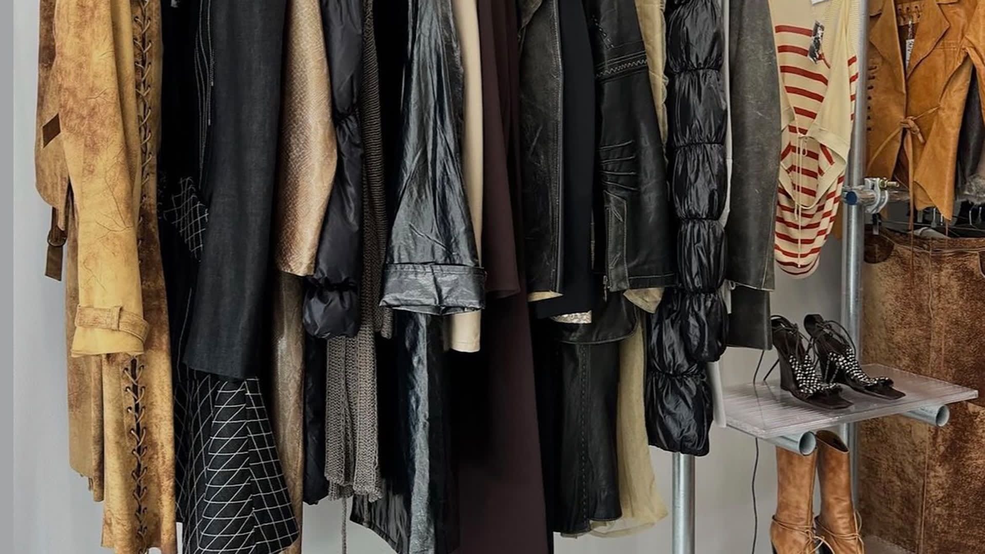 Collectie van diverse kledingstukken aan hangers, met leer, gestructureerde stoffen en een gestreept shirt. Inclusief hoge hakken met accenten.