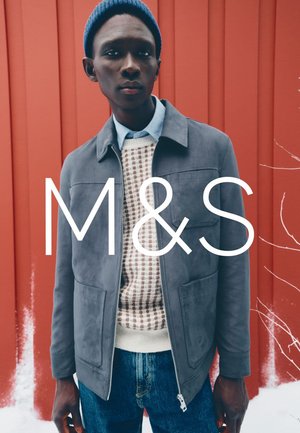Gray suede jacket with a zip front, paired with a cream and brown patterned sweater, and blue jeans. Displayed against a red backdrop.
