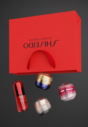 Rode Shiseido geschenkdoos met handvat, met vier huidverzorgingsproducten: een rood serum en drie potjes in verschillende kleuren met etiketten.