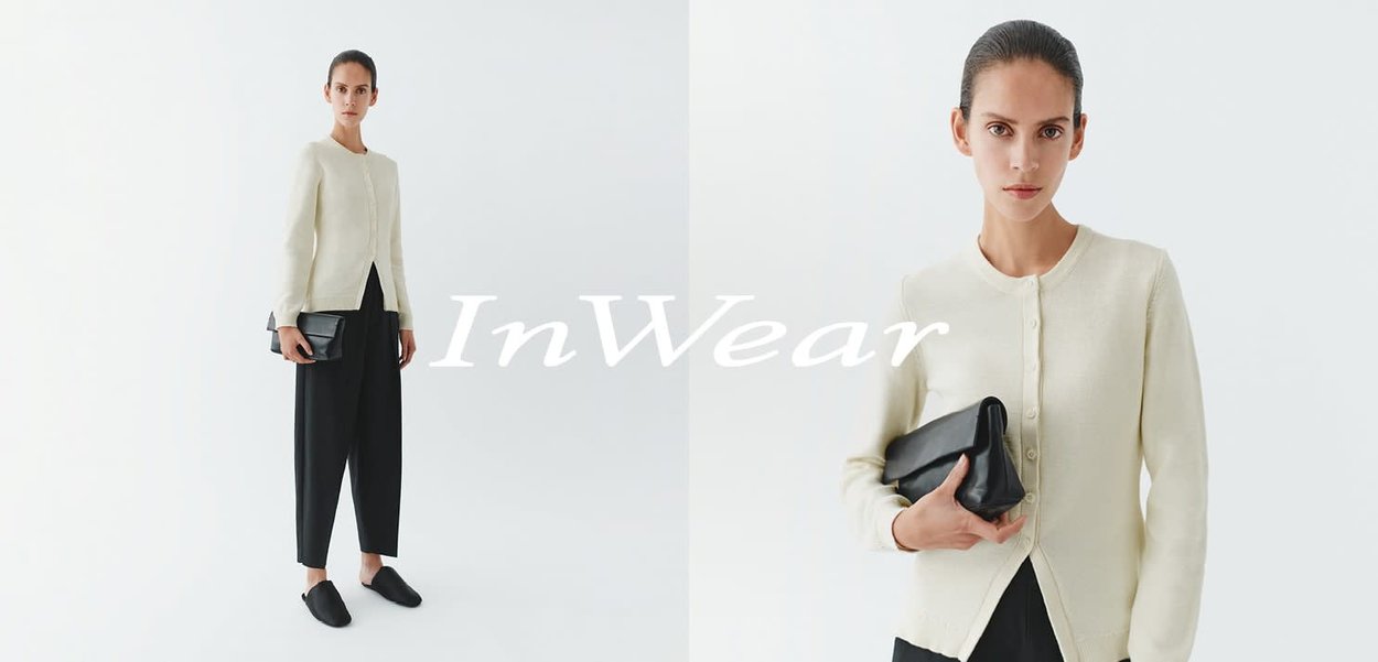 Hellbeige Cardigan mit rundem Ausschnitt, Knopfleiste und geripptem Stoff, kombiniert mit schwarzen Hosen mit weitem Bein und einer schwarzen Clutch.