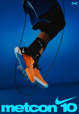 Baskets Nike Metcon 10, avec une tige orange, des accents noirs et une semelle bleue. Design texturé avec un laçage visible et des détails de logo.