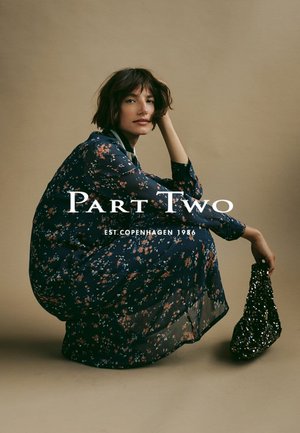 Abito floreale navy con maniche lunghe e silhouette ampia e fluida. Abbinato a una borsa a tracolla nera con paillettes texturizzate. Sfondo di colore semplice.