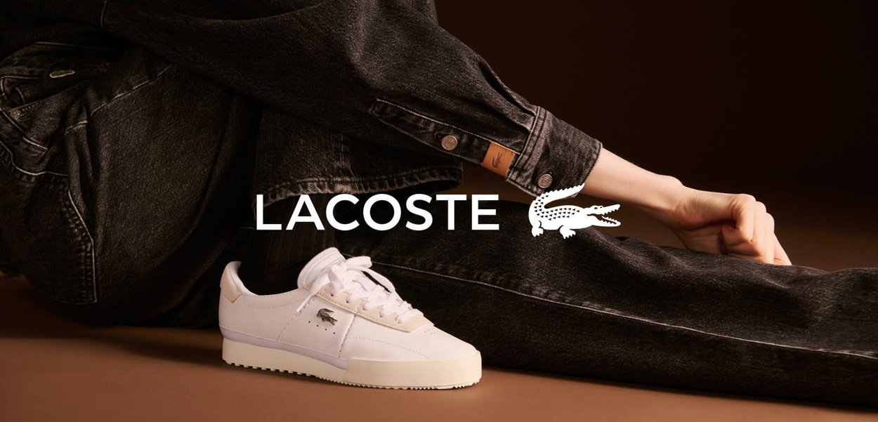 Białe sneakersy Lacoste z teksturowanej skóry, z wyszywanym logo, w połączeniu z ciemnoniebieskimi dżinsami. Prosty design na sznurówki i gumowa podeszwa.