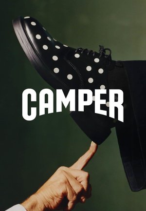 Schwarzer Schuh mit weißen Punkten, balanciert auf dem Zeigefinger einer Person vor einem dunklen grünen Hintergrund, mit dem Schriftzug "CAMPER" darüber.