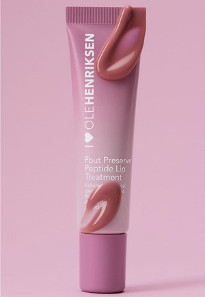 Tube de traitement pour les lèvres Pout Preserve Peptide d'Ole Henriksen avec des échantillons de baume à lèvres rose sur le tube, sur fond rose.
