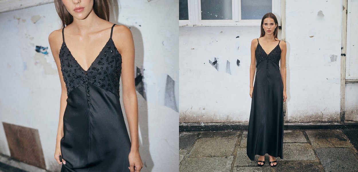 Schwarzes Maxikleid aus Satin mit V-Ausschnitt, verziertem, perlenbesetztem Oberteil und Knopfdetail am Rücken. Glatte Textur, minimalistisches Design.