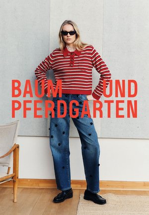 Rot und weiß gestreifter Strickpullover mit drei Knöpfen, kombiniert mit blauen Jeans mit schwarzen Blumenapplikationen. Schwarz gefütterte Loafers getragen.