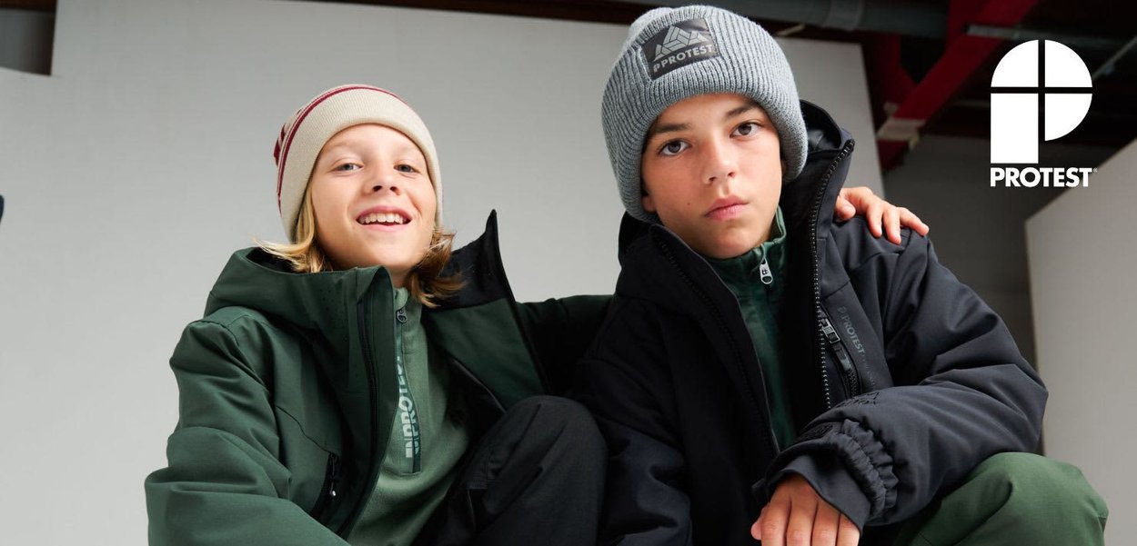 Two boys in winter jackets and beanies sit close together, one smiling and the other serious, with a PROTEST logo in the corner.