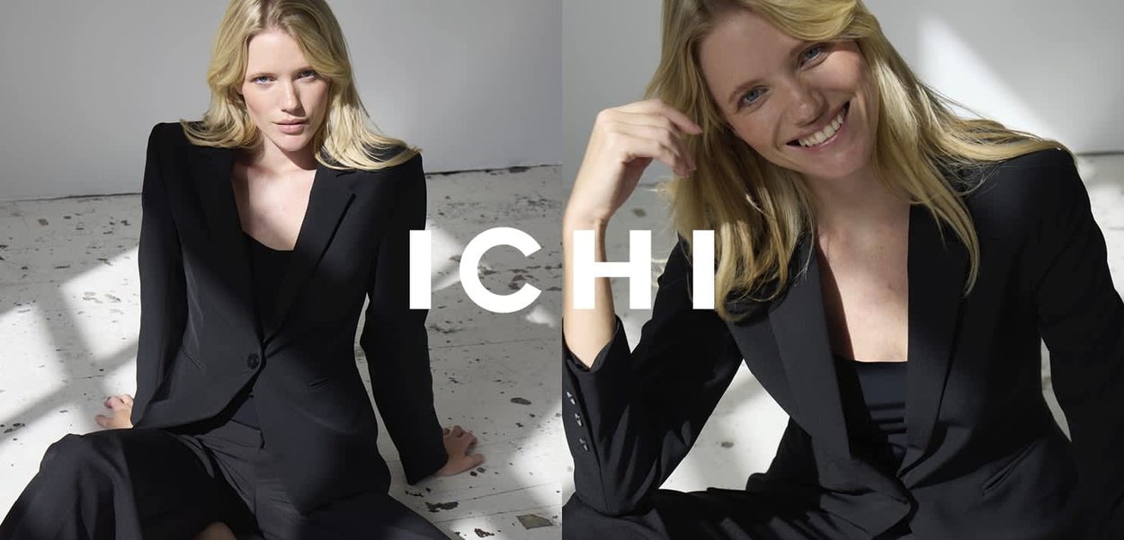 Schwarzer Blazer und Hose, maßgeschneidertes Design, glatte Textur, Modell sitzt auf hellem Boden, natürliches Licht hebt den Stoff hervor.