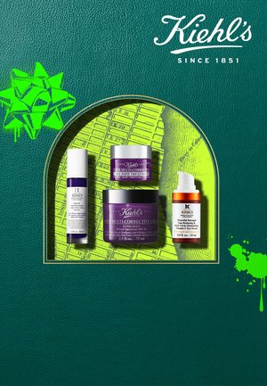 Drei Kiehl's Hautpflegeprodukte: ein lila Glas, eine weiße Tube und eine orange Pipettenflasche, auf einem grünen strukturierten Hintergrund mit einer Geschenk- Grafik.