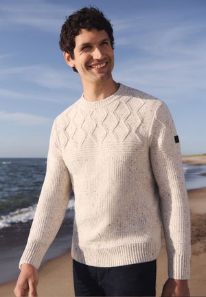 Cremfarbener Strickpullover mit einem Muster aus erhöhten Rauten und gerippten Bündchen. Verfügt über einen strukturierten Stoff und ein dezentes Logo am Ärmel.