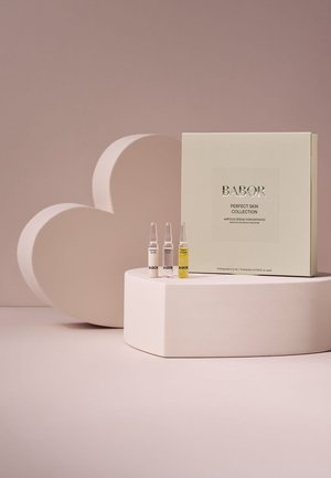 Kolekcja ampułek serum Babor Perfect Skin z trzema małymi fiolkami oznaczonymi jako Perfect Glow, Hydra Plus i Multi Vitamin na różowym piedestale.